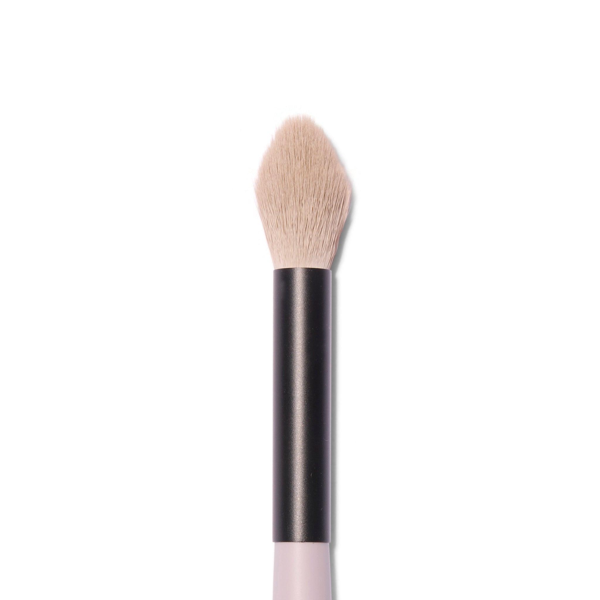 Close up view of the head of the Jo Leversuch Untitled No. 1 Multi-Use Brush. The natural hair bristles are a dusty pink grey. The wooden handle is painted a rosy grey.