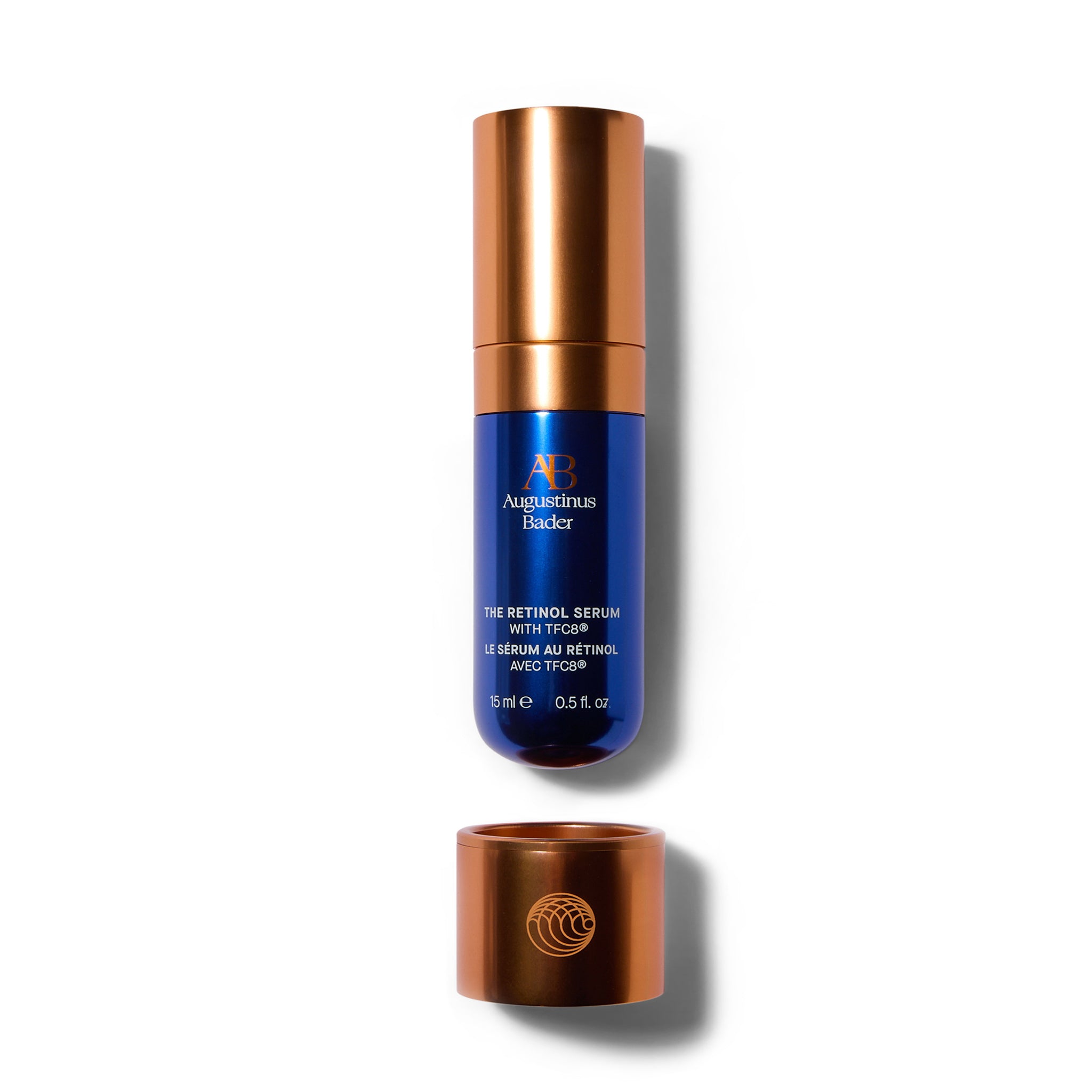A deep blue bottle with matte metallic orange accents and cap sitting just above a matte metallic orange cup that holds the bottle.