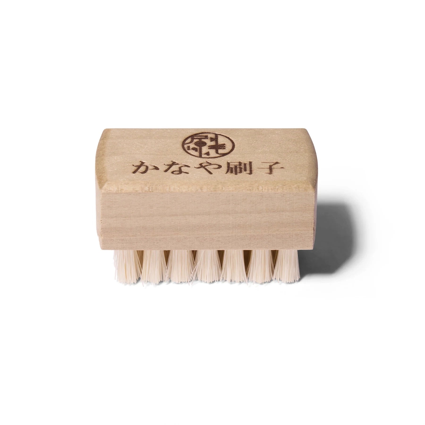 Small light colored wooden nail brush with natural hair bristles and Japanese lettering.