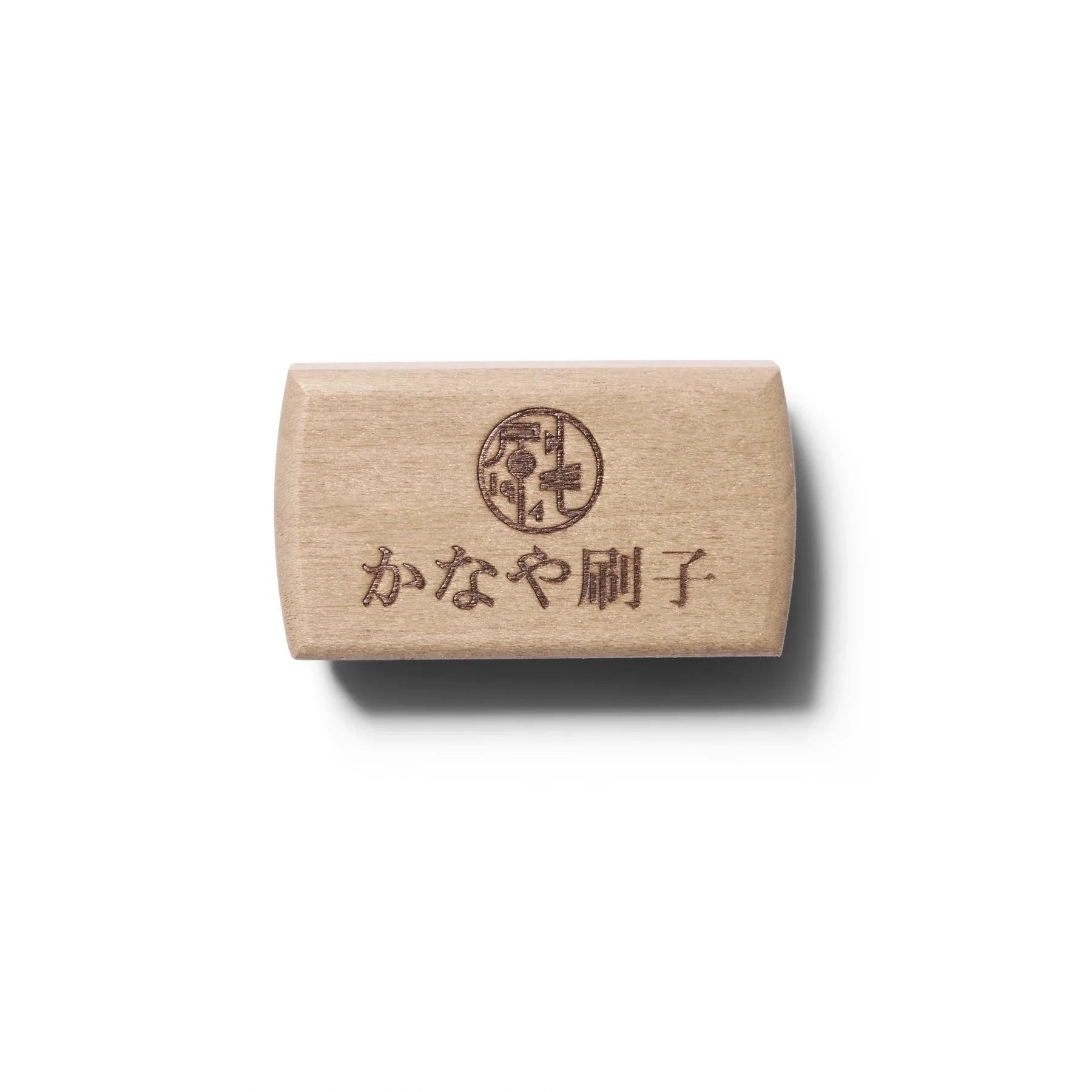 Small light colored wooden nail brush with natural hair bristles and Japanese lettering photographed from the top.