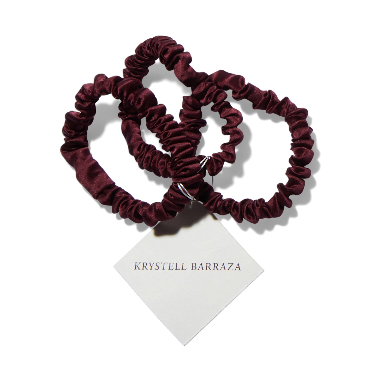 Three 6 Krystell Barraza silk hair ties in Plum with the logo tag attached. 