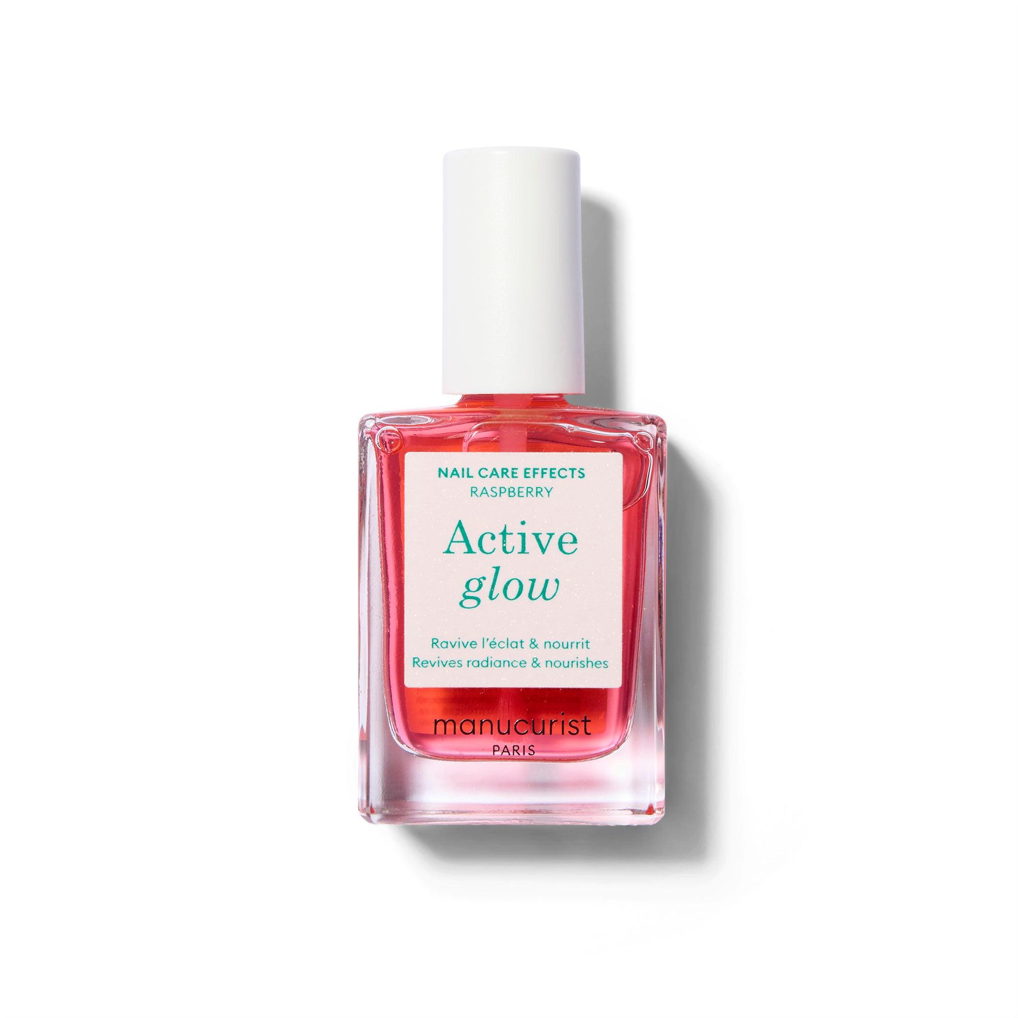 A clear bottle of nail polish with label with green text and a white cap. The polish color is a sheer, light raspberry pink.
