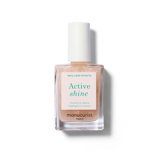 A clear bottle of nail polish with label with green text and a white cap. The polish color is a sheer nude with very soft sparkle.