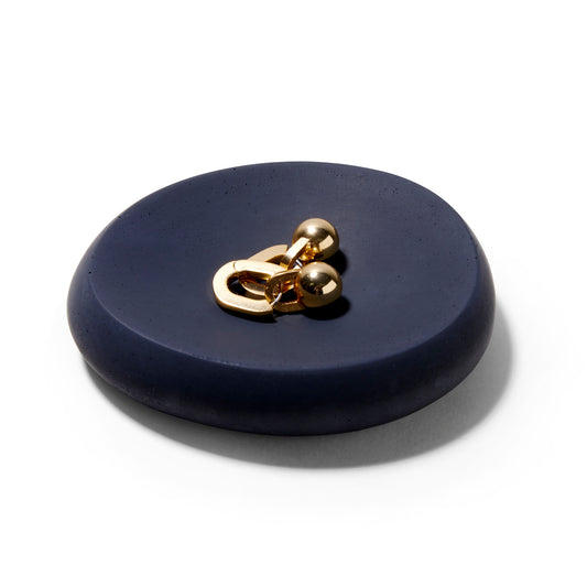 The Mitmo concrete soap dish matte black concave dish with small gold earrings on it.