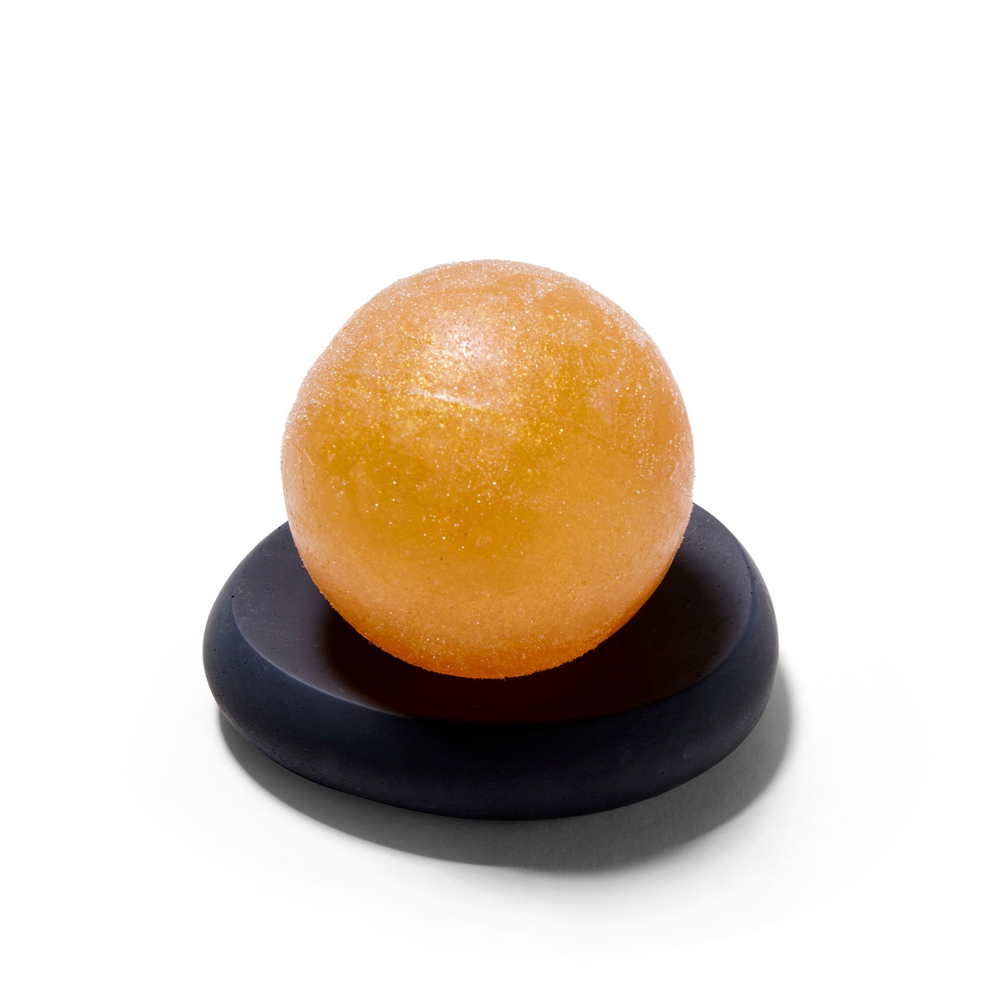 The Mitmo concrete soap dish matte black concave dish with a gold sphere soap on it.