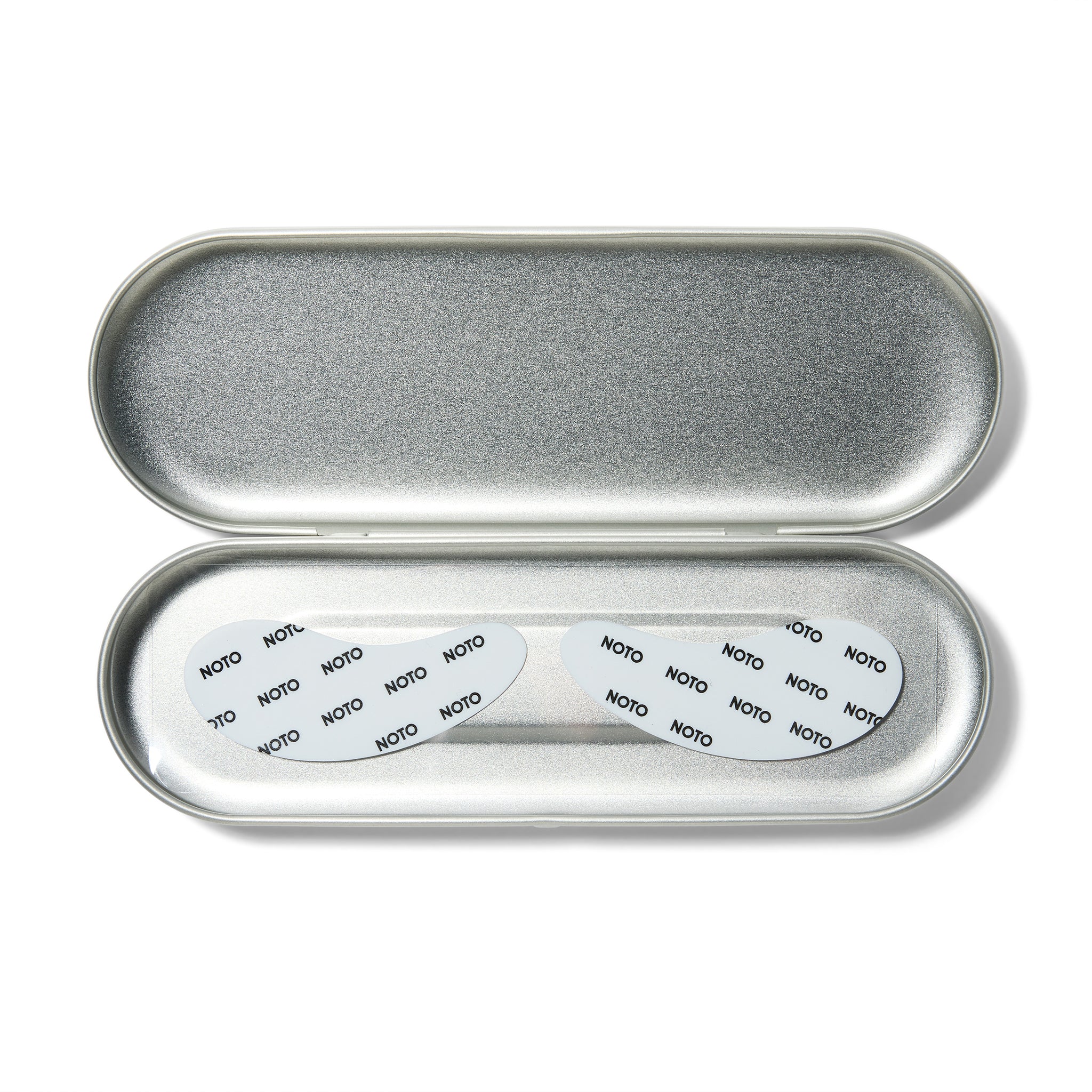 An open silver oval case with white tear drop shaped eye patches with Noto written on them.