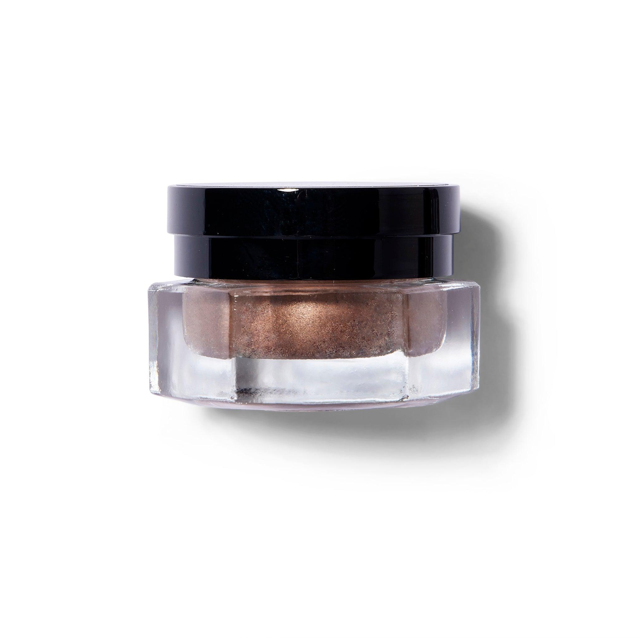 Glass container with Rituel De Fill Ash & Ember product inside in a coppery shade.
