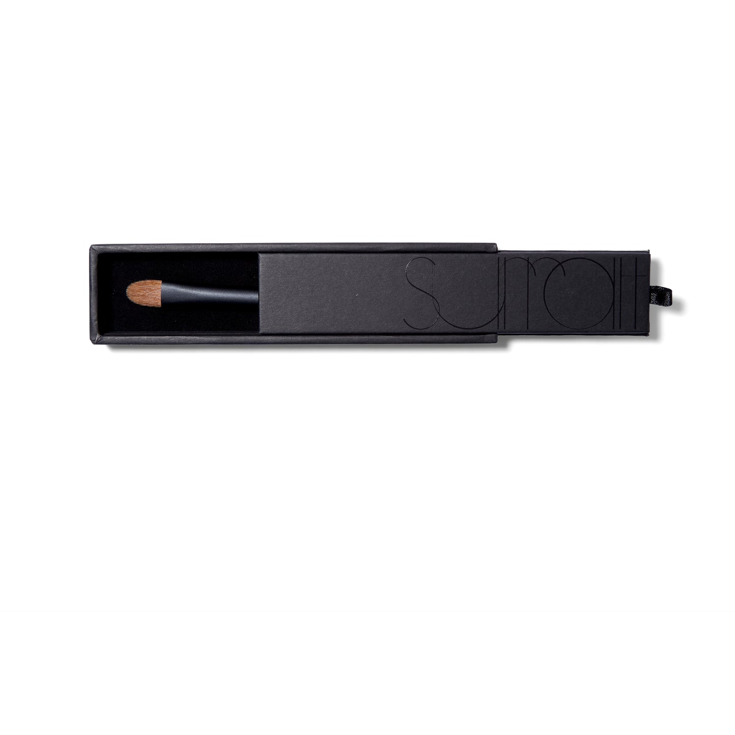 The Surratt Perfectionniste Complexion brush. in a black sturdy box. The handle is black with subtle purple shimmer. The natural bristles are brown and in a soft curved taper. 