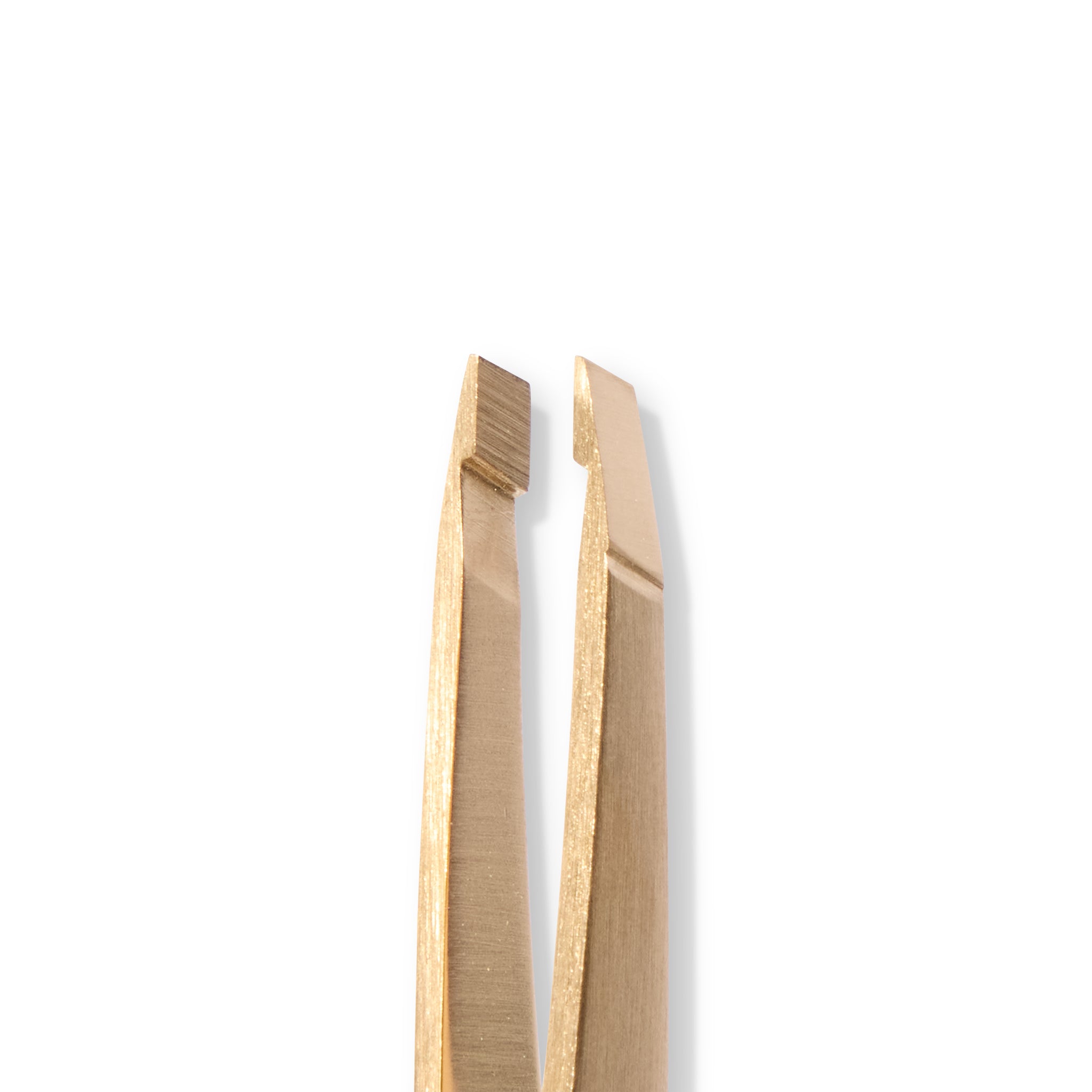 Close up of a pair of gold-colored tweezers on a white background