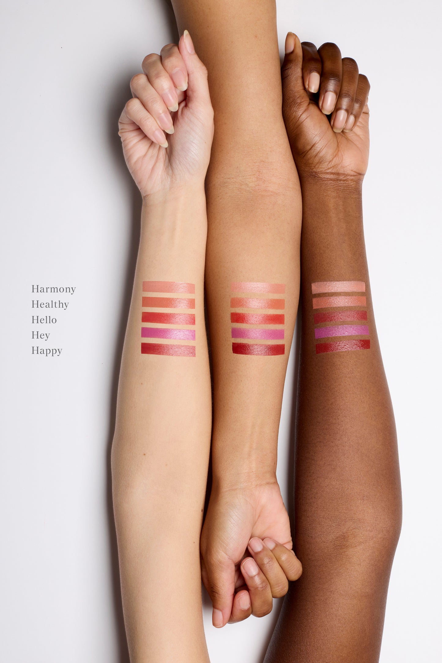 Three arms lined up next to each other with cream blush swatches on the skin. There are five swatch stripes on each of the three arms. The arm on the left is fair, the middle is golden and the arm on the right is deep. Their nails are unpainted and their hands are semi-closed in a relaxed state.