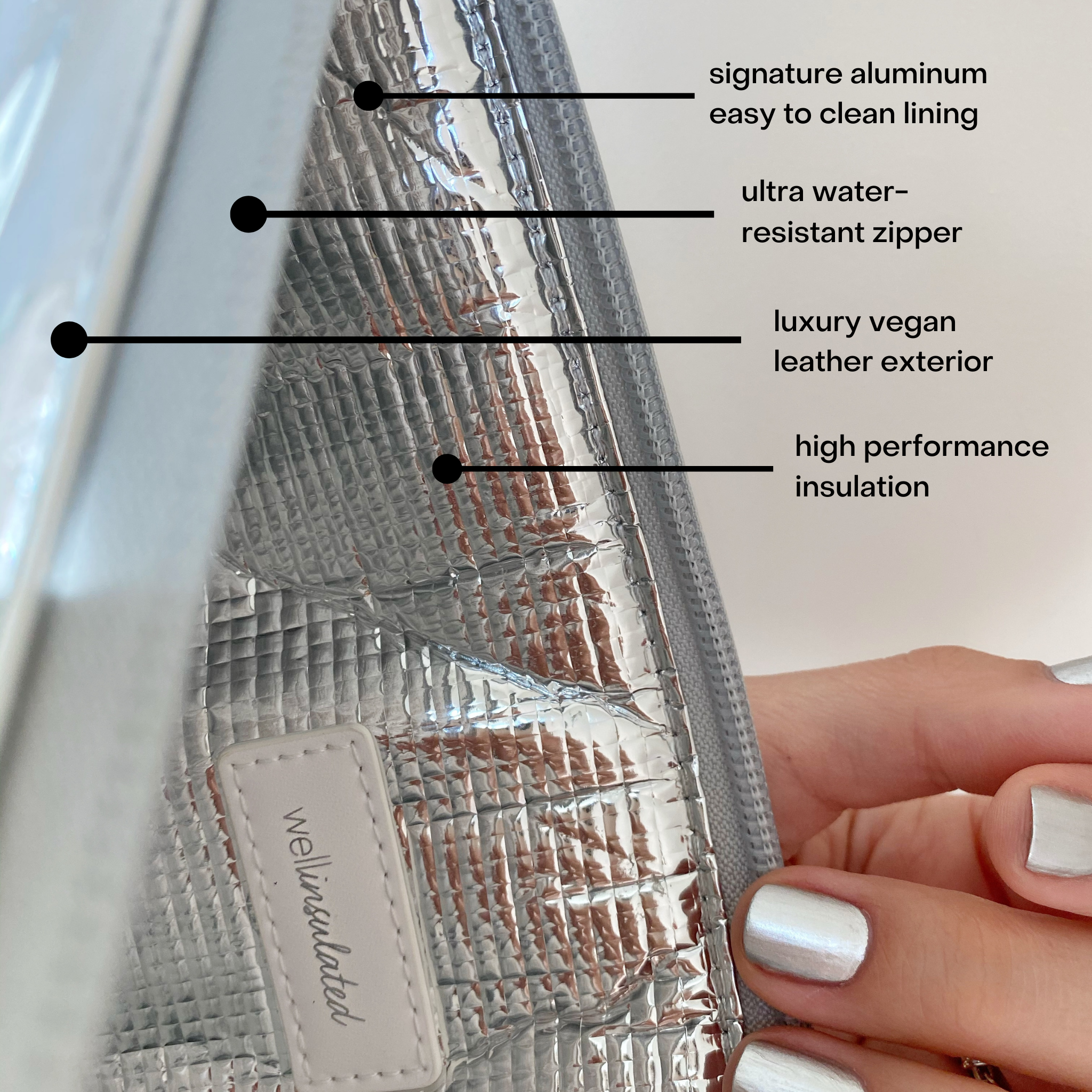 Close up view of the inside of the Performance Tech Pouch. The silver pouch is open showing the silver interior of the bag. There is text on the image describing the various features of the bag. There is a hands with silver nail polish touching the zipper.