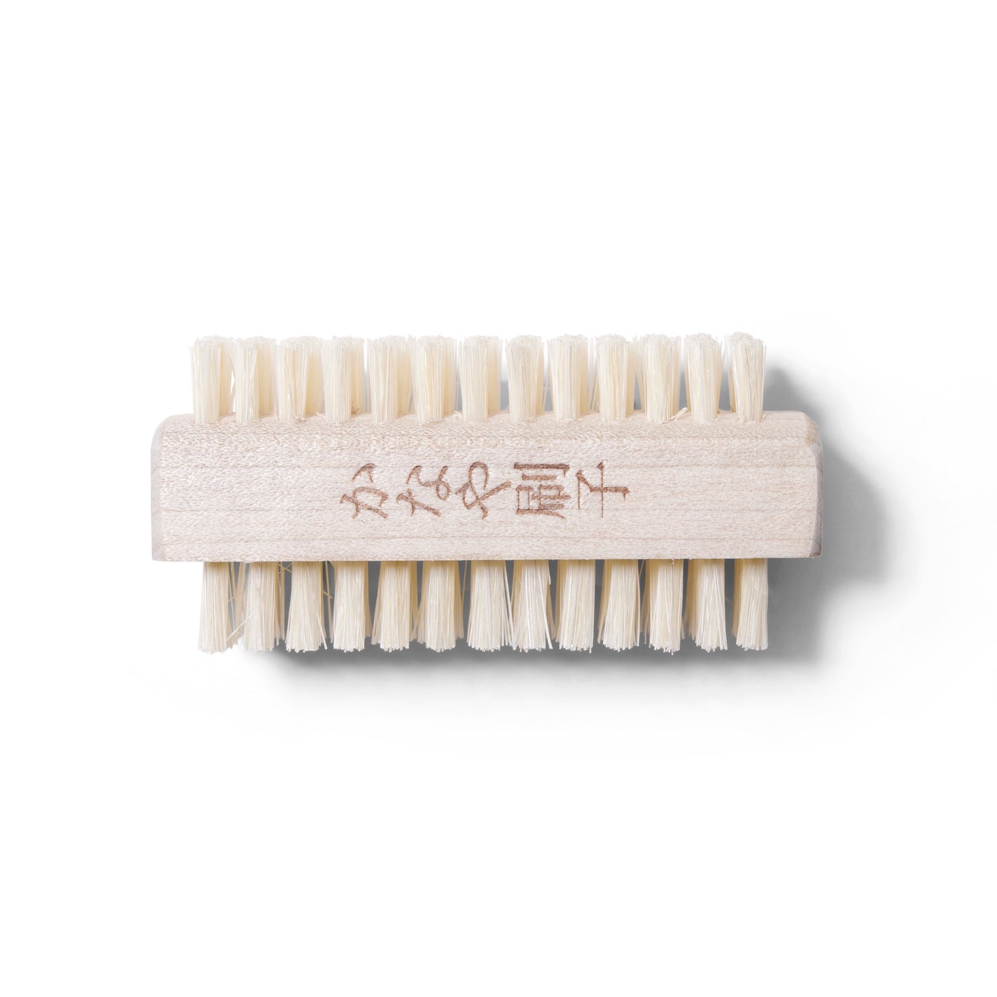 Front view of the dual sided Kanaya Nail Brush. The Brush is made of light colored boar bristles and light wood.