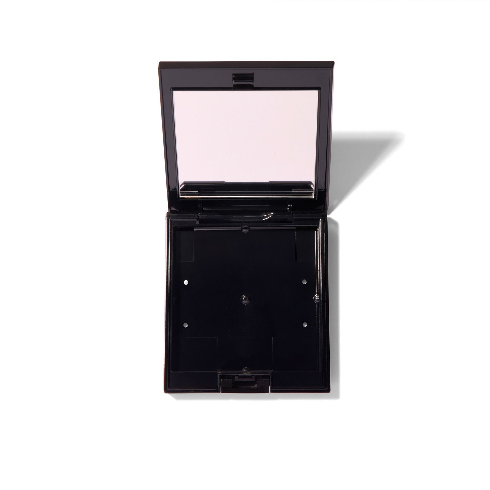 The black Compact Case I, open and showing the mirror and the empty case with space for blushes. 