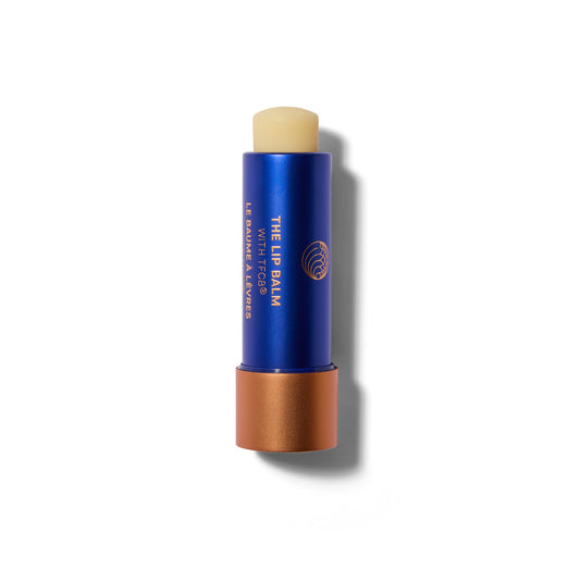 A waxy lip balm stick in a blue and matte  metallic tube. The cap is off. The lip balm is wound up slightly so you can see the balm bullet.