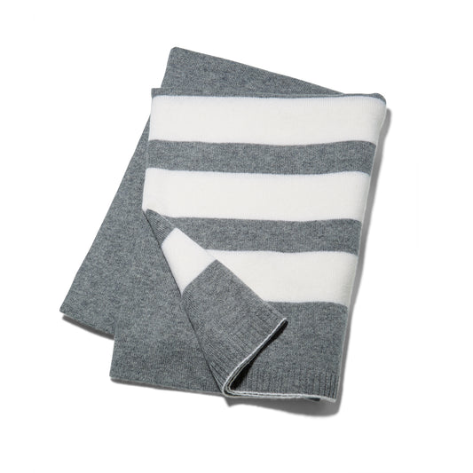 The Reed Clarke Cashmere Travel blanket, a folded grey blanket with wide white stripes. 