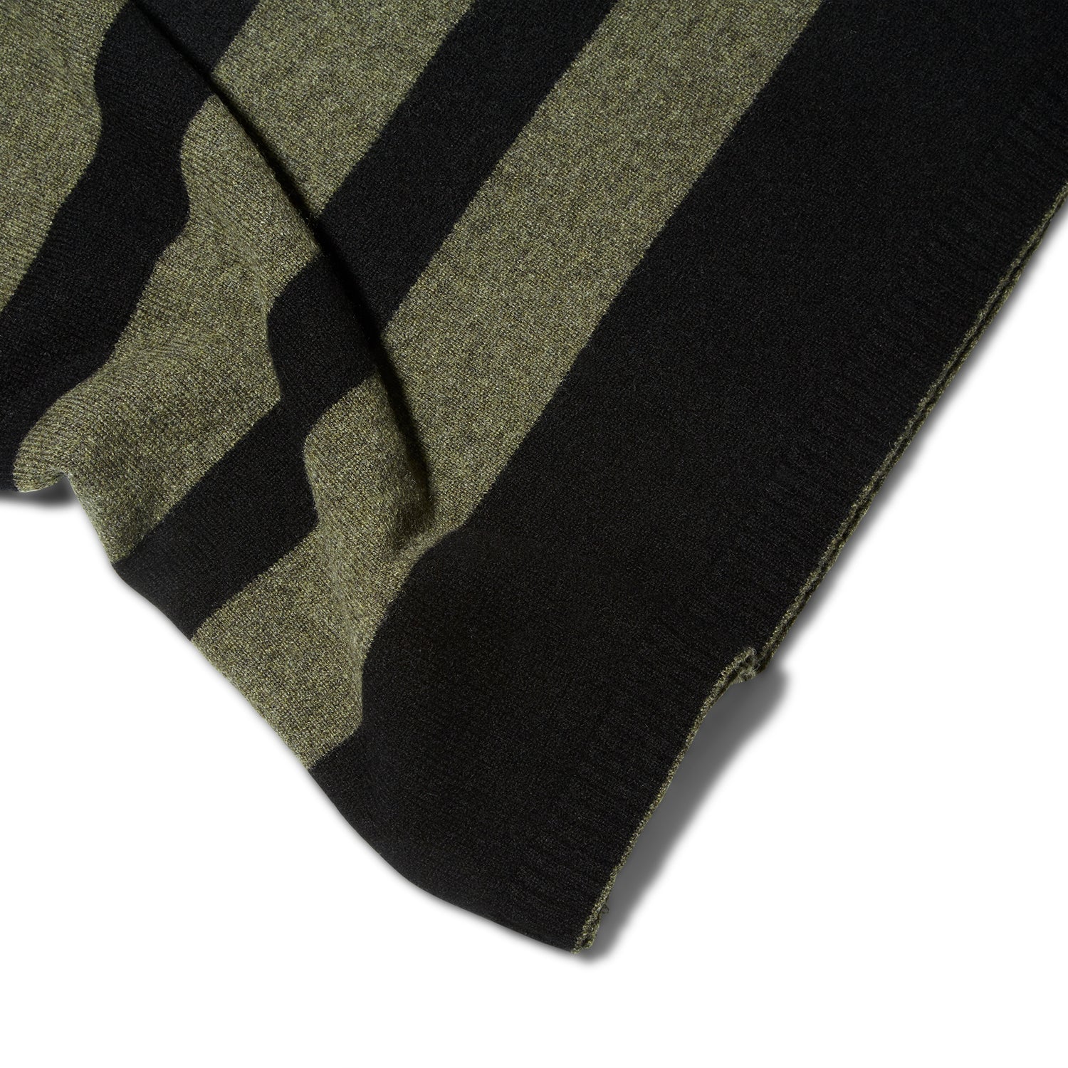 A close up detail of the edge of the Reed Clarke Cashmere Travel blanket, a folded black blanket with wide olive green stripes. 