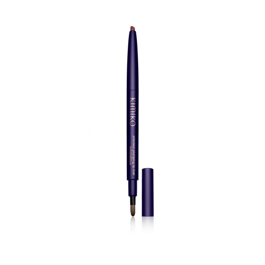 Front view of the Kimono Plumping Lipliner Pencil. The pencil is wound up to show the product. The cap is off and to the right of the pencil. You can see the brush on the end.