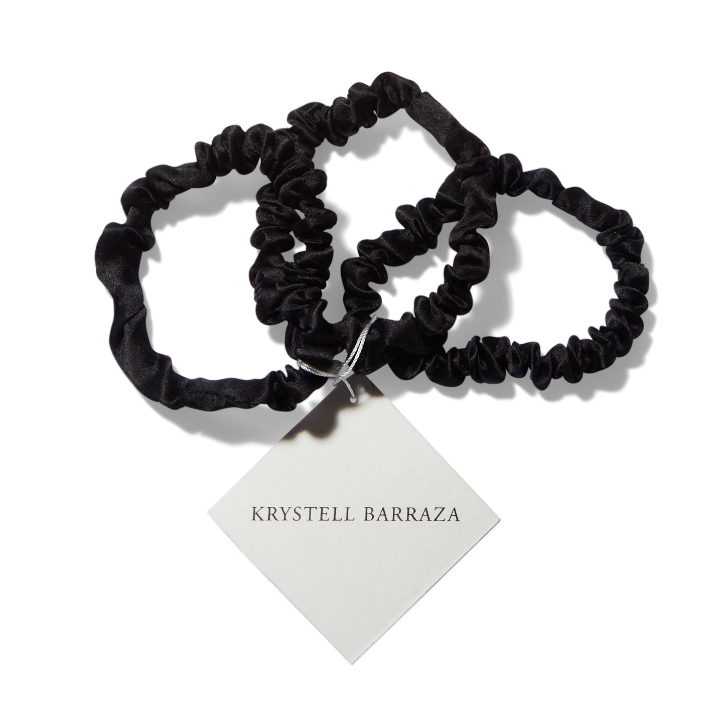 Three 6 Krystell Barraza silk hair ties in Onyx with the logo tag attached. 