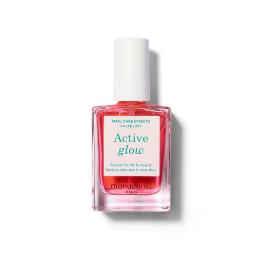 A clear bottle of nail polish with label with green text and a white cap. The polish color is a sheer, light raspberry pink. 