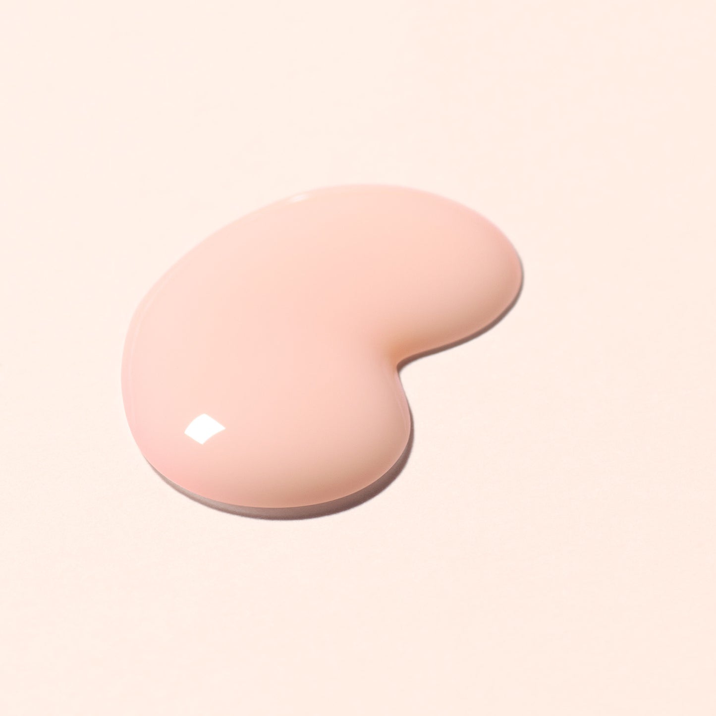 A bean shaped dollop of the Active Smooth nail polish - an opaque peach -on a light peach background.