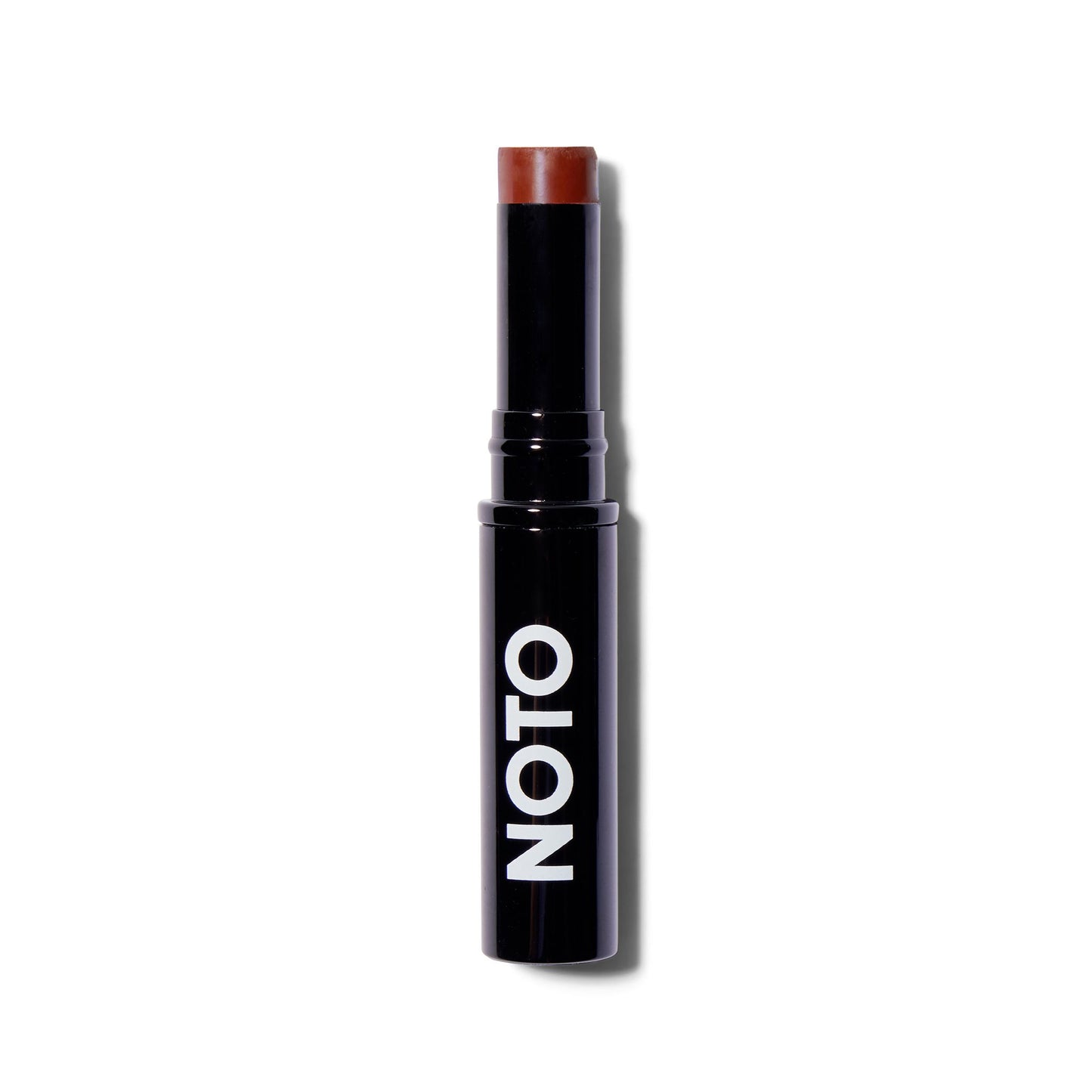 Front view of the Noto Organics Multibenne Stick in Fluxus, a warm russet shade. The cream blush is wound up out of the component so you can see that product. The component is black with a white logo. 