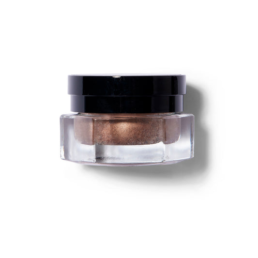 Glass container with Rituel De Fill Ash & Ember product inside in a coppery shade. 