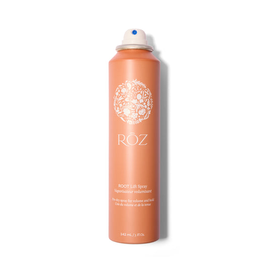 A tall thin terracotta colored metal bottle with white text and logo. The cap is off showing the aerosol nozzle.