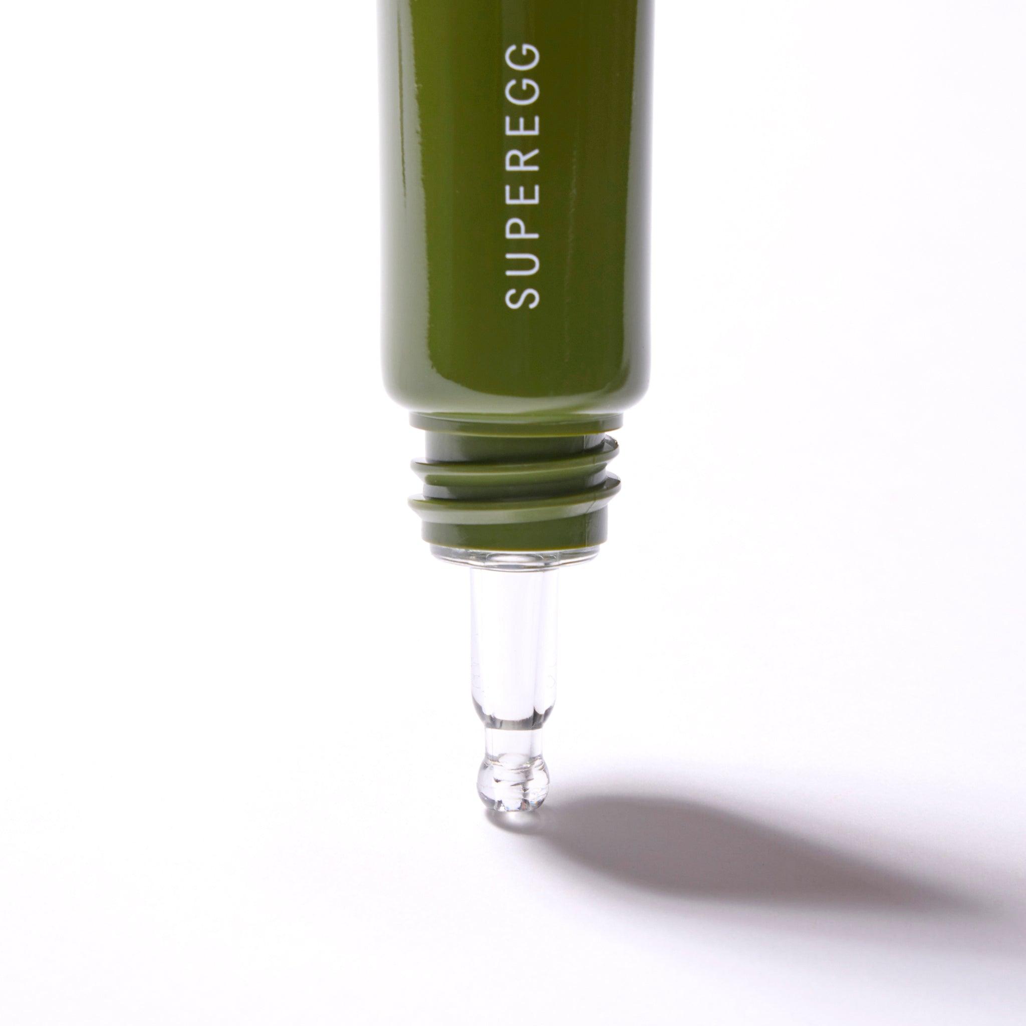 A close up of the tip of a green tube with white text. The cap is off and the tip is clear.