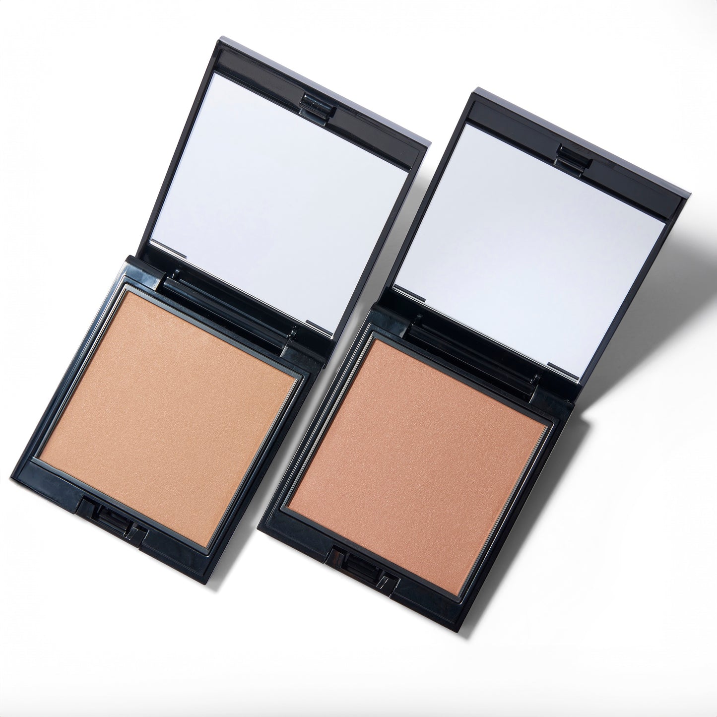 Two powder bronzer compacts next to each other at an angle. They are both open with the mirrors visible.