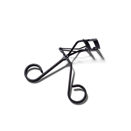 Overhead view of the matte black Surratt Relevee Eyelash Curler. The Lash curler is slightly open.