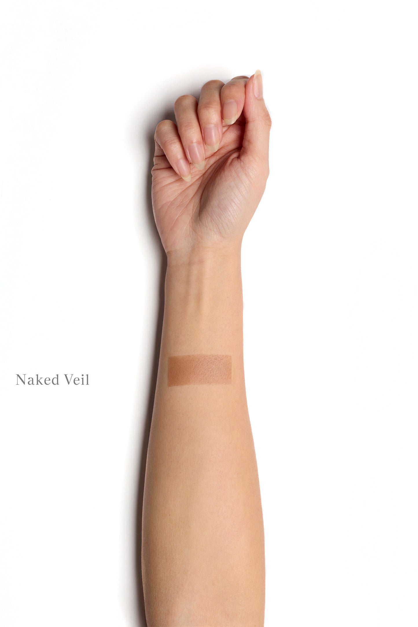 A swatch of a light taupe blush in a rectangle on a medium toned forearm. The hand is semi-closed in a resting position. There is no nail polish on the nails. 